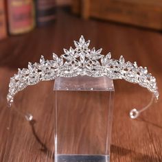 the tiara is sitting on top of a clear display case in front of a wooden table