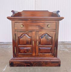 an old wooden cabinet with two doors and knobs on the front, sitting in a garage