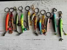 there are many different types of fishing lures on the table with key chains hanging from them