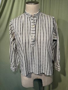 This is an adorable vintage blouse from the 60s or so. Labeled Gordon Peters, Man Tailored. No size tag. The bust measures 40" with measurements below. Made of a black & white cotton blend in a vertical stripe pattern. The pullover blouse closes down the front bodice with plastic buttons. The blouse has long sleeves with button cuffs. Hem is straight with small vents on the side seams. The collar has two buttonholes at the top for a button link or other pin type closure, which is not included. The inside of the collar has 3 small buttons, most likely had some sort of removable tie at some point in time.    The blouse is in very good condition!  No damage. No stains or soil. Super cute!  If you have never worn vintage before, please measure yourself!! Vintage sizes run smaller than today's Classic Plaid Tops For Daywear, Striped Top With Placket For Daywear, Daywear Top With Striped Collar, Classic Striped Tops For Daywear, Fall Striped Tops With Collar, Retro Collared Top With Placket, Retro Long Sleeve Top With Striped Collar, Retro Collared Top For Work, Classic Top With Striped Collar For Daywear