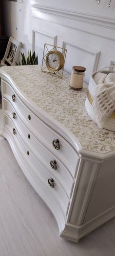 a white dresser sitting in a bedroom next to a window