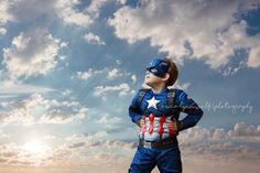 a young boy dressed as captain america standing in front of the sun