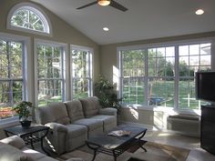 a living room filled with furniture and large windows