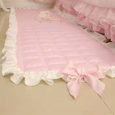 a pink and white baby crib with ruffled bedspread on the floor