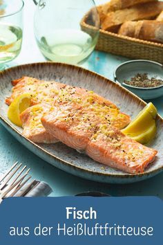 a fish is on a plate with lemon wedges and bread in the back ground