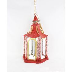 a red and gold lantern hanging from a chain on a white background with the light turned on