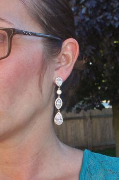 "A gorgeous new set, made using premium rose gold and CZ components. The earrings feature halo set pear jewels, set in rose gold. They are separated by smaller, crown set CZ jewels, and connect to a halo style marquise. The bottom stone on the earring is a larger halo pear. Earrings are post style, with sterling silver post secured to the top of the top jewel. Earrings measure 2 1/4\" long. You can also choose to purchase the set, with the matched pendant necklace. I offer two styles and sizes. Wedding Bridal Earrings In Rose Gold With Halo Design, Rose Gold Halo Bridal Earrings For Wedding, Dangle Bridal Earrings With Halo Design, Dangle Bridal Earrings With Halo Design For Wedding, Rose Gold Teardrop Bridal Earrings For Wedding, Bridal Chandelier Earrings, Jewel Earrings, Bridal Earrings Chandelier, Pear Earrings