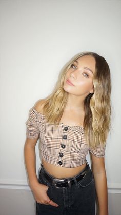 a woman standing in front of a white wall with her hands on her hips and looking off to the side