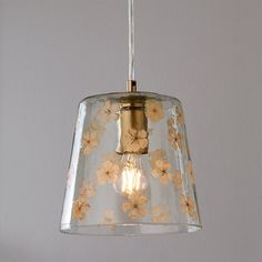 a light that is hanging from a ceiling with flowers on the glass and gold trim