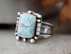 "The setting is a Cushion 15mm x 11mm Sand Hill Turquoise Cabochon that is in a Bezel setting accented with beads and triangle wire. This stone is opaque and is light blue with gray matrix. At its widest the shank is 3/8\" then narrows to 1/8\" for a comfortable fit. This ring cannot be resized. Size 11 Sand Hill Turquoise, natural stone, Sterling Silver Statement Ring, Handmade jewelry. This chic cocktail ring has been handmade using the purest 925 Sterling Silver that has been fused, stamped and lightly oxidized. This is a one of a kind chunky ring perfect for the chic jewelry wearer that wants that southwest jewelry vibe. It is an eye popping ring that will catch the attention of western jewelry lovers. Sand Hill Turquoise is becoming harder and harder to find as the mine from which it Thick Silver Ring, Western Boho Chic, Town Outfits, Turquoise Statement Ring, Chunky Ring, Southwest Jewelry, Square Stone, Jewelry Metal, Chunky Rings