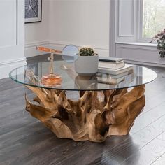 a wooden table with glass top in front of a potted plant on the floor