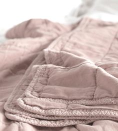 an unmade bed with pink linens and white sheets on top of each other