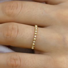 a woman's hand wearing a gold ring with five small diamonds on the band