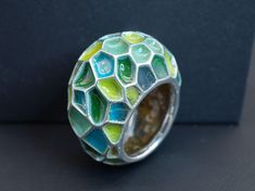 A gorgeous enameled ring in a size 7 1/2. Featuring a beautiful selection of blue and green enamel colors with a lovely emerald hidden on the back of the ring for the wearer to admire. This sculptural ring wears very comfortably and will bring a splash of bright color and joy to any day; sure to pair well with any outfit. Materials: Glass Enamel, Natural Emerald, Sterling Silver Unique Green Open Ring Jewelry, Unique Multicolor Enamel Ring, Modern Green Enamel Jewelry, Green Enamel Round Ring, Unique Green Ring Jewelry, Green Enamel Rings As A Gift, Modern Green Round Dome Ring, Unique Hand Painted Enamel Rings, Unique Blue Enamel Ring