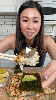 a woman is holding chopsticks over a dish of sushi and rice with avocado