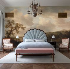 a bedroom with a large painting on the wall and a chandelier hanging from the ceiling