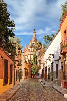 an old cobblestone street with buildings and trees on both sides in the background