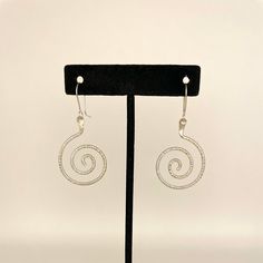 Sterling silver swirl dangle earrings with French hook wires, a unique and elegant design. Handmade by Zuni artist, Carlton Jamon. Measurements: 2" x 0.9" (including wire) Weight: 0.19oz (5.4g) Material: sterling silver (silver925) Handmade Silver Swirl Earrings, Spiral Silver-plated Wire Earrings, Nickel Free Silver Swirl Earrings, Silver Swirl Wire Wrapped Earrings, Spiral Silver Plated Wire Earrings As Gift, Silver Wire Wrapped Swirl Jewelry, Spiral Silver Plated Wire Earrings For Gift, Silver Swirl Wire Wrapped Jewelry, Silver Wire Wrapped Jewelry With Swirl Design