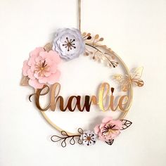 a wooden sign with flowers hanging from it's side and the word charlie spelled in gold