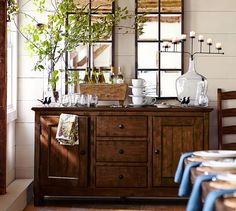 an old photo of a dining room with plants on the sideboard and wine bottles