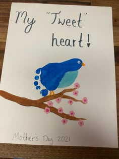 a blue bird sitting on top of a tree branch next to a sign that says, my tweet heart