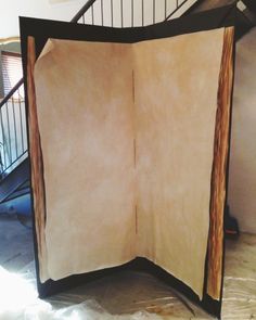 an open book sitting on top of a wooden floor next to a spiral stair case