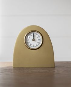 a gold clock sitting on top of a wooden table