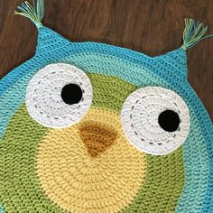 a crocheted owl rug with eyes and ears on top of a wooden floor