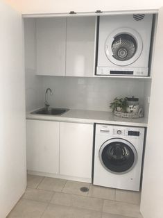 a washer and dryer in a small room with white cabinets on the wall