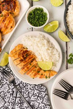 the meal is ready to be eaten on the table with limes, rice and chicken