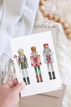 a hand holding up a card with three nutcrackers