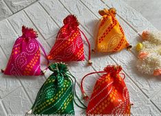 six bags with different designs on them sitting on a white tableclothed surface, all lined up and ready to be used as favors