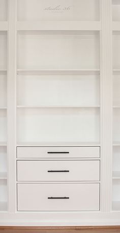 an empty white bookcase with drawers and shelves