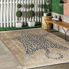 a leopard rug is on the floor in front of a white fence with potted plants