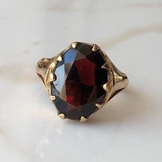 A Vintage 9 carat yellow gold Garnet ring. This beautiful piece holds a large deep red stone in a gold setting. CONDITION: Wear consistent with age and use. Please see photos for more detail. HALLMARKED 9 CARAT GOLD, ASSAYED IN LONDON 1977 STONE SIZE (SETTING): 14mm x 11mm  SETTING HEIGHT: 5mm BAND WIDTH: 2mm RING SIZE: US: 6 | UK: L 1/4 WEIGHT: 3.2 grams (UZZ) Gold Garnet Ring, Garnet Gem, Garnet Ring, Red Band, Lovely Ring, Garnet Rings, Red Stone, Signet Ring, Deep Red