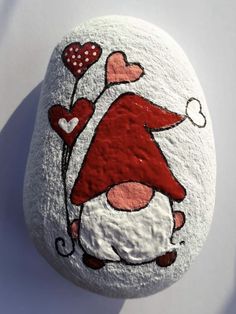 a painted rock with an image of a gnome holding hearts on it's back