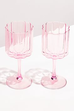 two pink glass cups sitting on top of a white table next to eachother