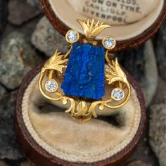 This lovely circa 1900 18K yellow gold Egyptian revival pin features an engraved floral design, centered with a lapis carving of a face. The lapis is accented with four (4) bezel set, round old European cut diamonds. The pin measures 24.1mm long by 20.9mm wide and is finished with a sturdy 14K yellow gold hinged and locking pin back and charm hook. Egyptian Revival Jewelry, Egyptian Jewelry, Egyptian Revival, Diamond Brooch, European Cut Diamonds, Jewelry Case, Ancient Egyptian, Licorice, A Face