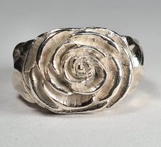 a close up of a silver ring on a white surface with a flower in the middle