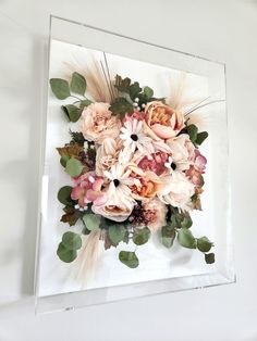 an arrangement of flowers in a glass frame