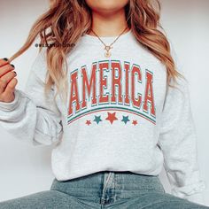 Our America Sweatshirt makes the perfect cozy 4th of July shirt for both men and women. This USA sweater is made with a super cozy sweater and the USA design is printed with a professional DTG Printing machine. We use eco-friendly water based inks that prints the image/designs on the shirt allowing the image to become part of the sweater so there is no peeling or cracking over time. If you have any questions please feel free to reach out and I will be happy to assist you.  HOW TO ORDER  1. Selec Red Patriotic Top For Fall, Long Sleeve American Style Cotton Sweatshirt, American Style Cotton Long Sleeve Sweatshirt, Patriotic Crew Neck Top For Fall, Americana Long Sleeve Tops With American Flag Print, Americana Crew Neck Top With Relaxed Fit, Americana Long Sleeve Tops For 4th Of July, Long Sleeve Americana Tops For 4th Of July, Relaxed Fit Americana Crew Neck Top