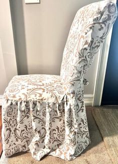 a chair covered in a white and brown damask fabric with an ornate design on the back