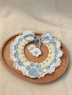 a crocheted baby bib on a wooden plate