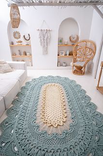 a crocheted rug on the floor in a room with white walls and furniture