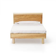 a bed with white sheets and wooden headboard on it's side, in front of a white background