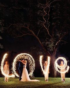 a bride and groom standing in front of the word love with sparklers around them