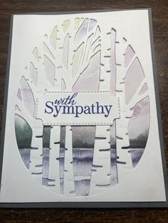 a card with the words sympathy written in blue and white on it, surrounded by trees