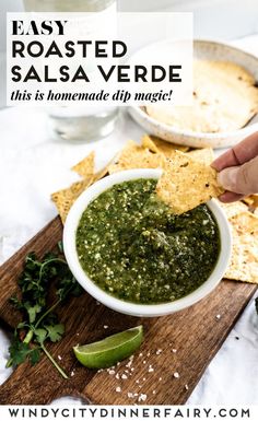 a person dipping salsa into a bowl with tortilla chips