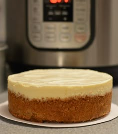 a cake sitting on top of a white plate next to an instant pressure cooker