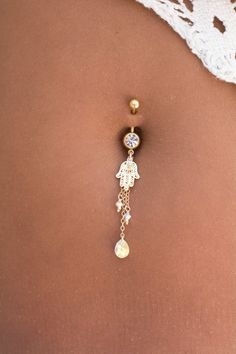 the back of a woman's stomach with a belly ring and dangling earrings on it